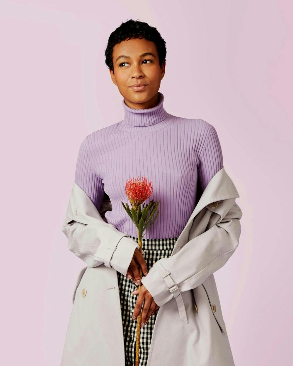 woman wearing turtleneck and holding a flower